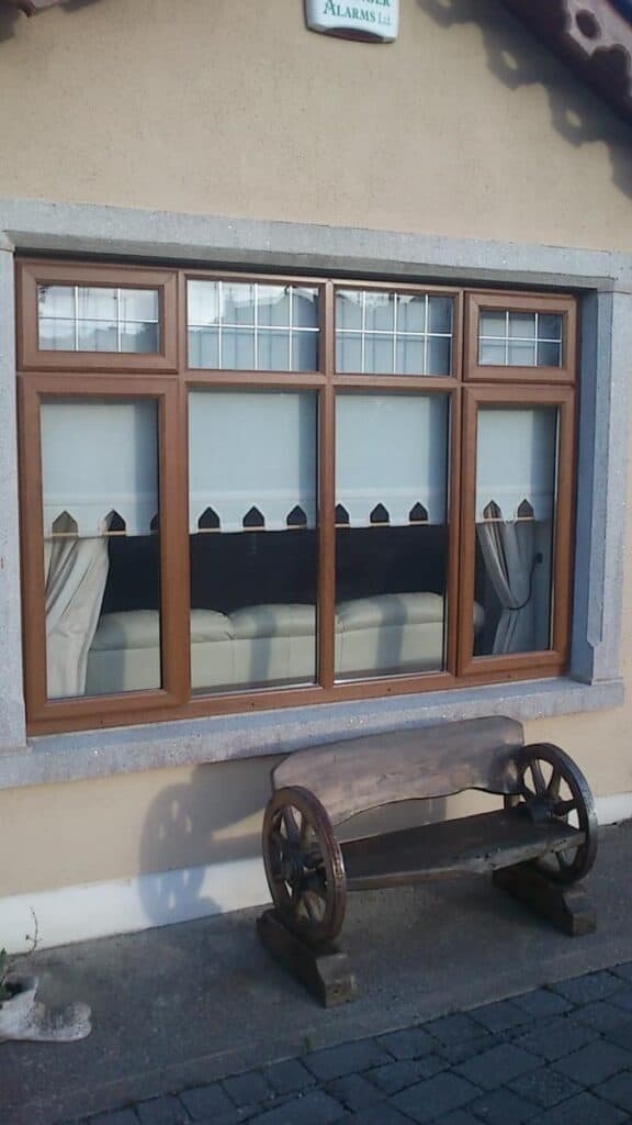 Wooden bench outside window with lace curtains.