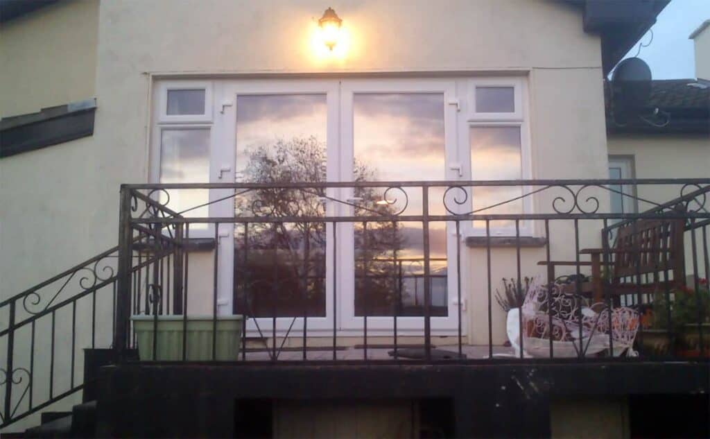 House balcony with sunset reflection on doors.