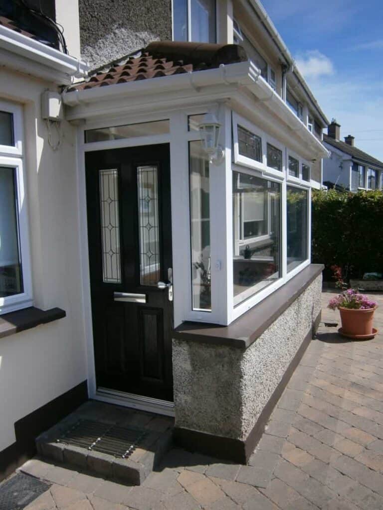 Modern house entrance with black door and windows.