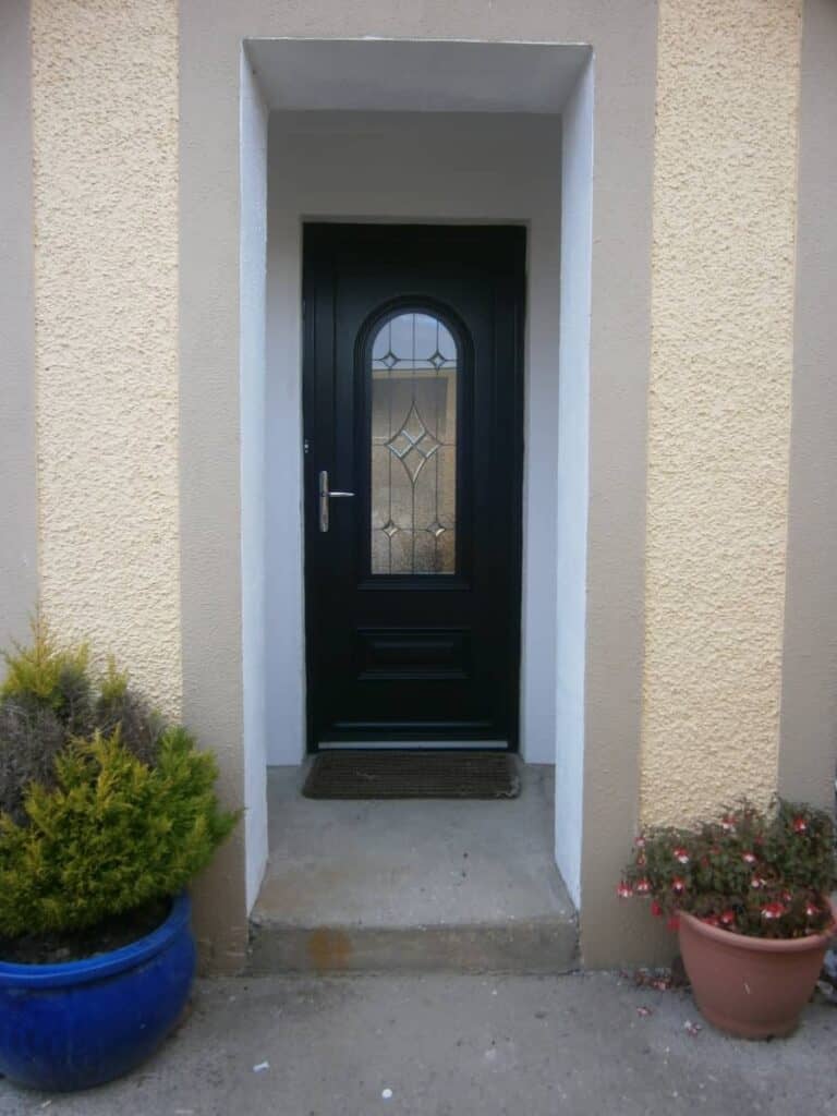 Black front door with potted plants outside.